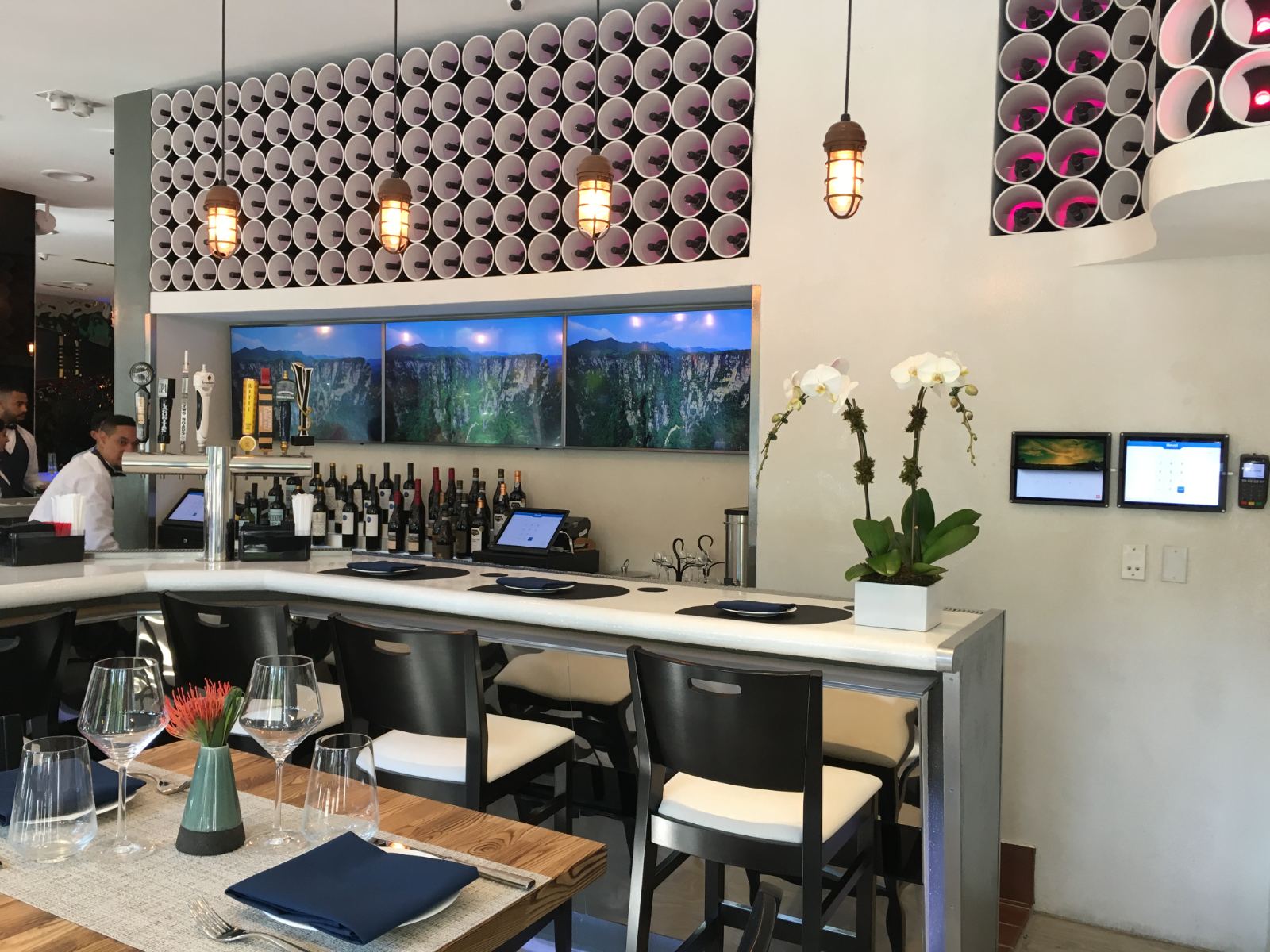 A four-panel display strip running scenery above a restaurant bar