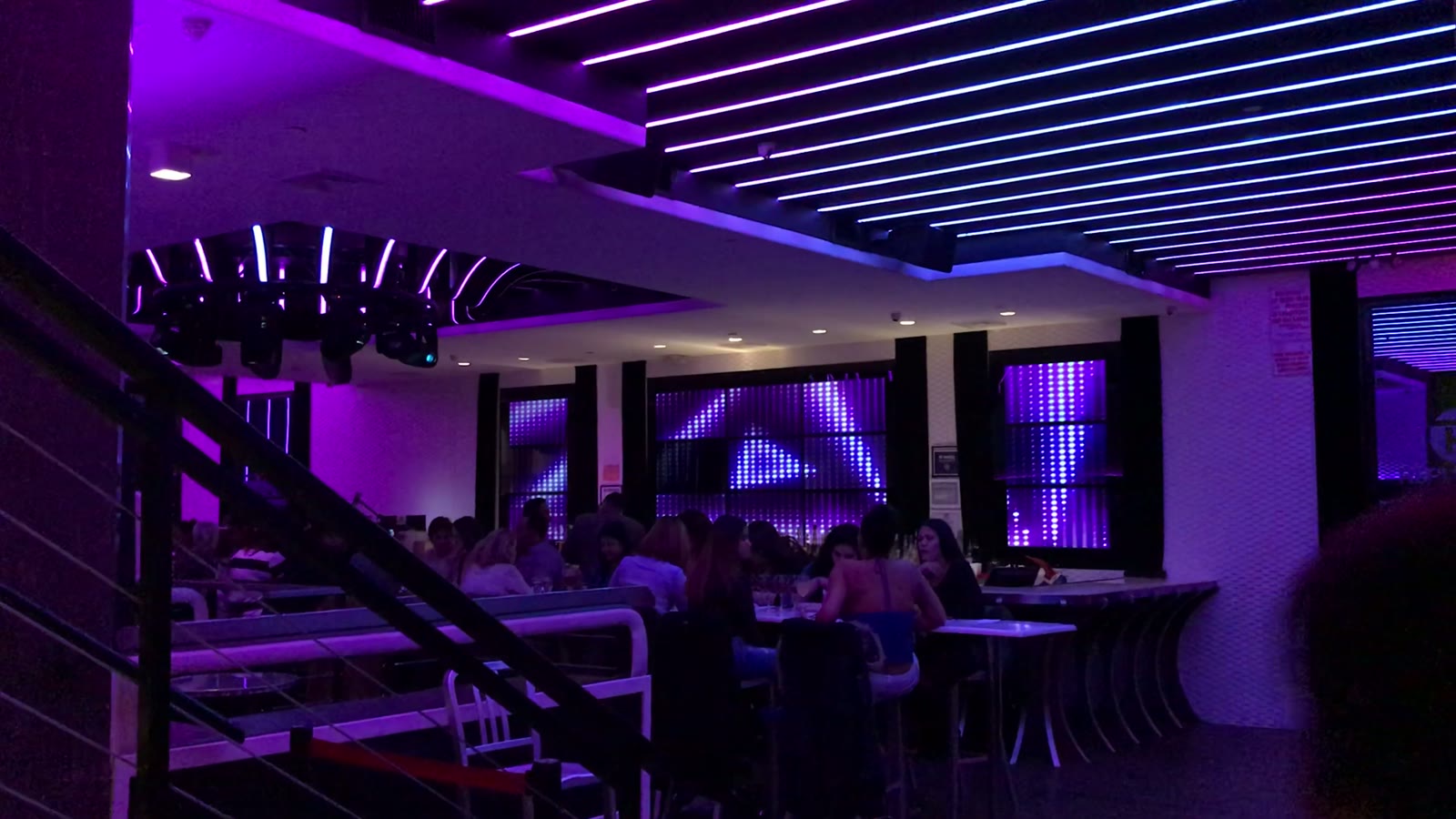 The club floor under violet ceiling LED with guests at the bar