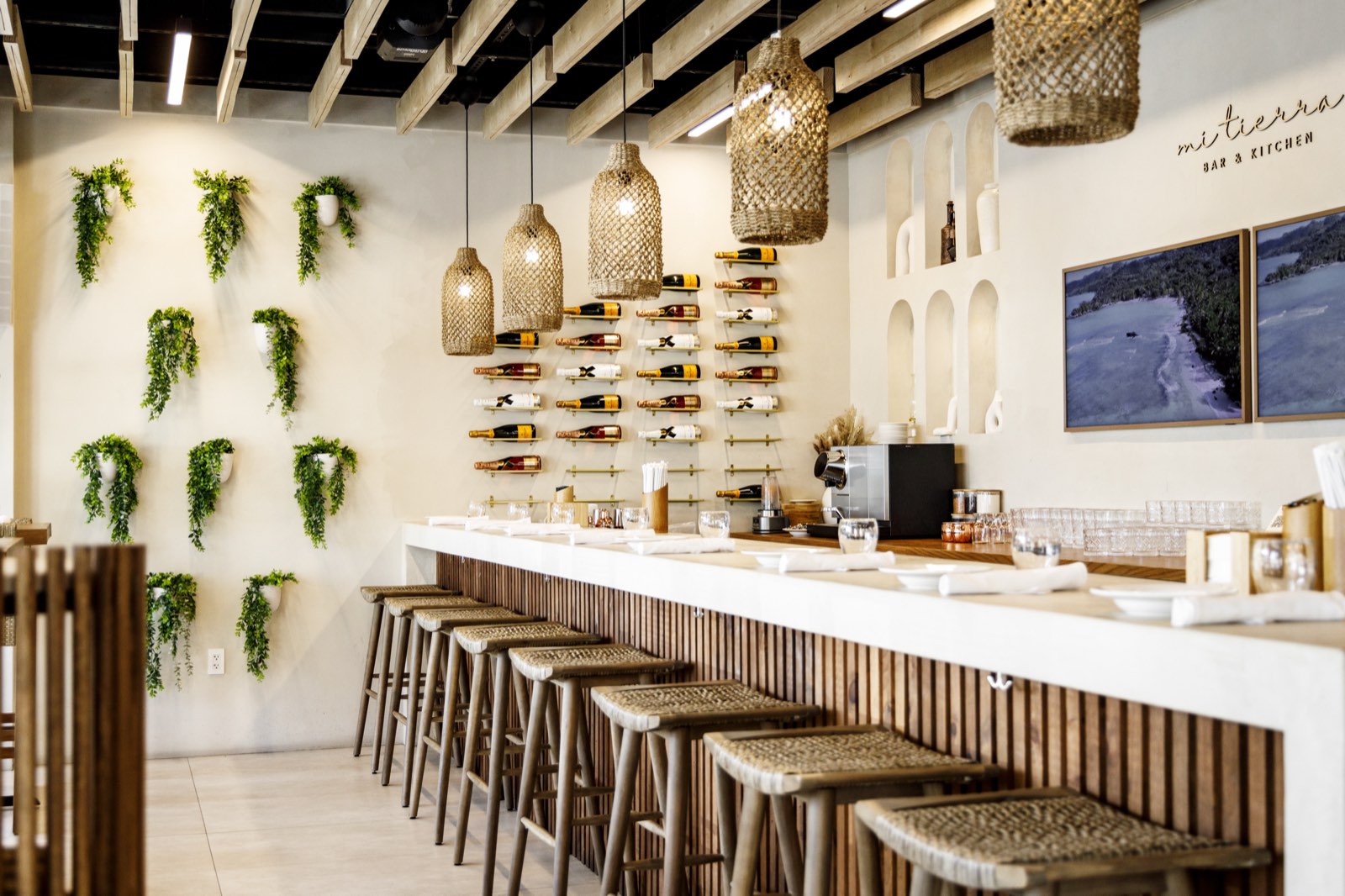 The bar and its wine wall under pendant lighting, with framed displays on the far wall