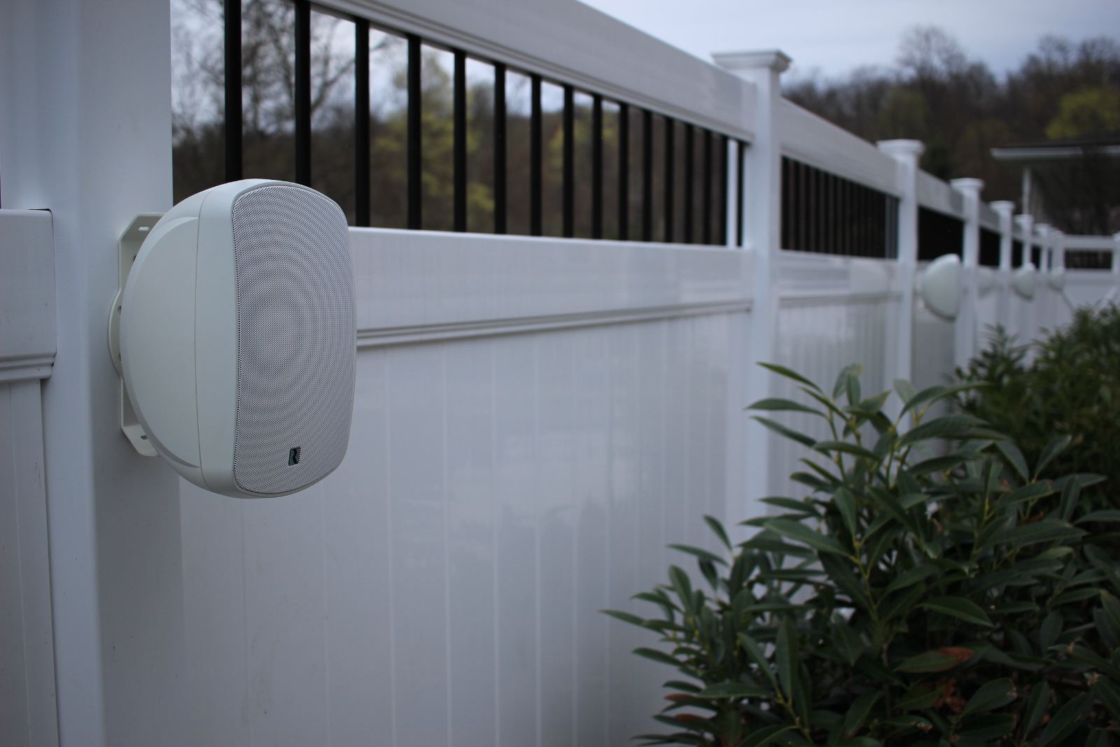 The same fence-mounted speaker at dusk