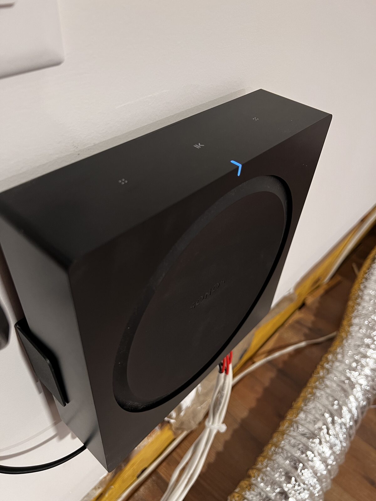 The subwoofer placed and wired against the wall